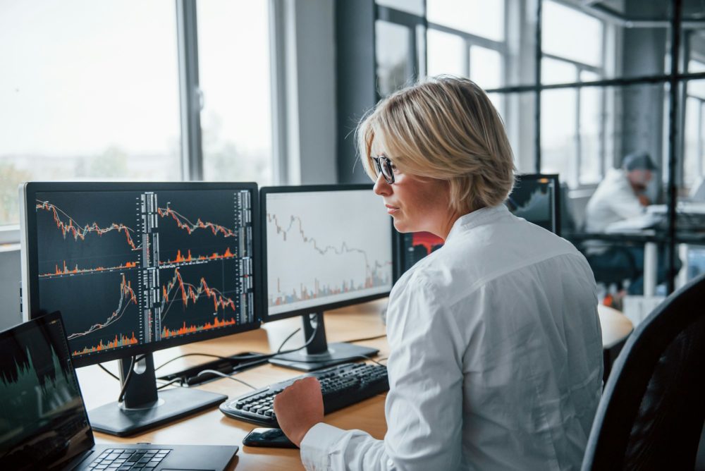 Female stockbroker in formal clothes works in the office with financial market