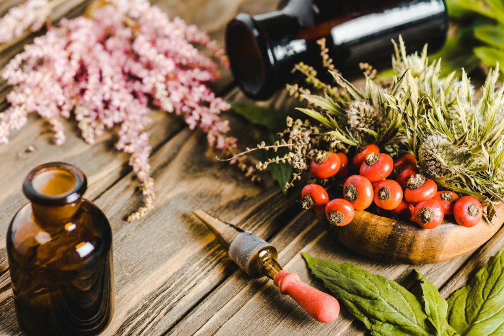 glass jars and flowers on wooden tabletop, alternative homeopathy medicine concept