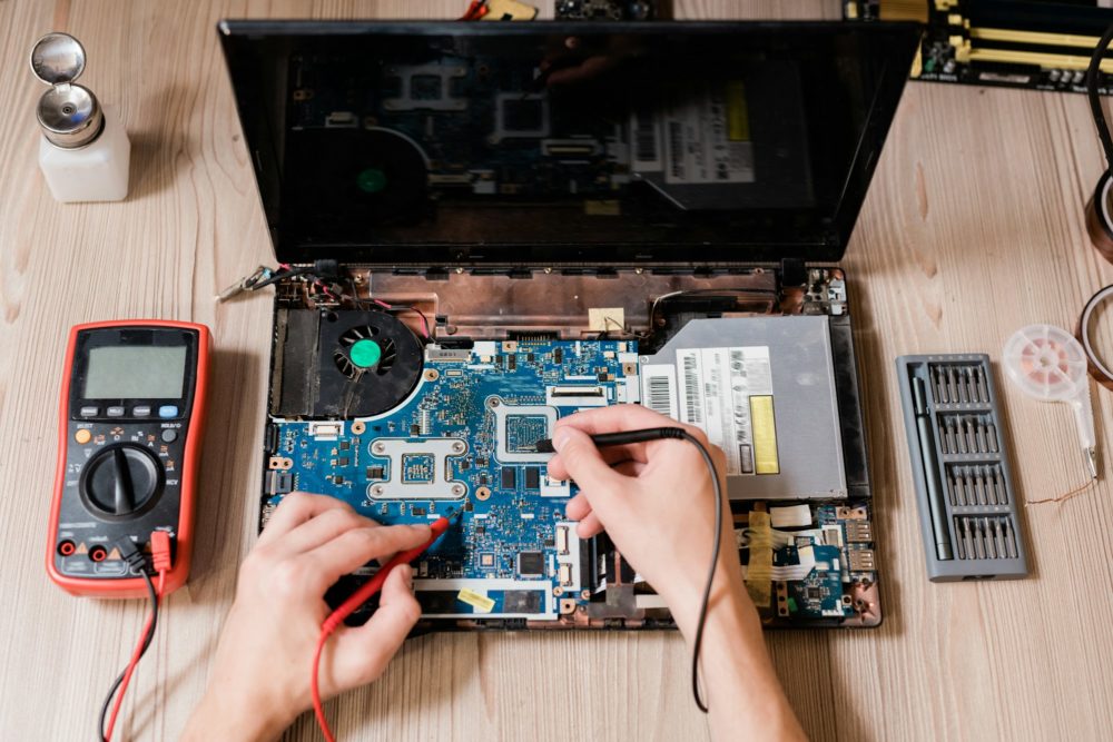 Hands of contemporary master using small soldering-irons to repair broken laptop