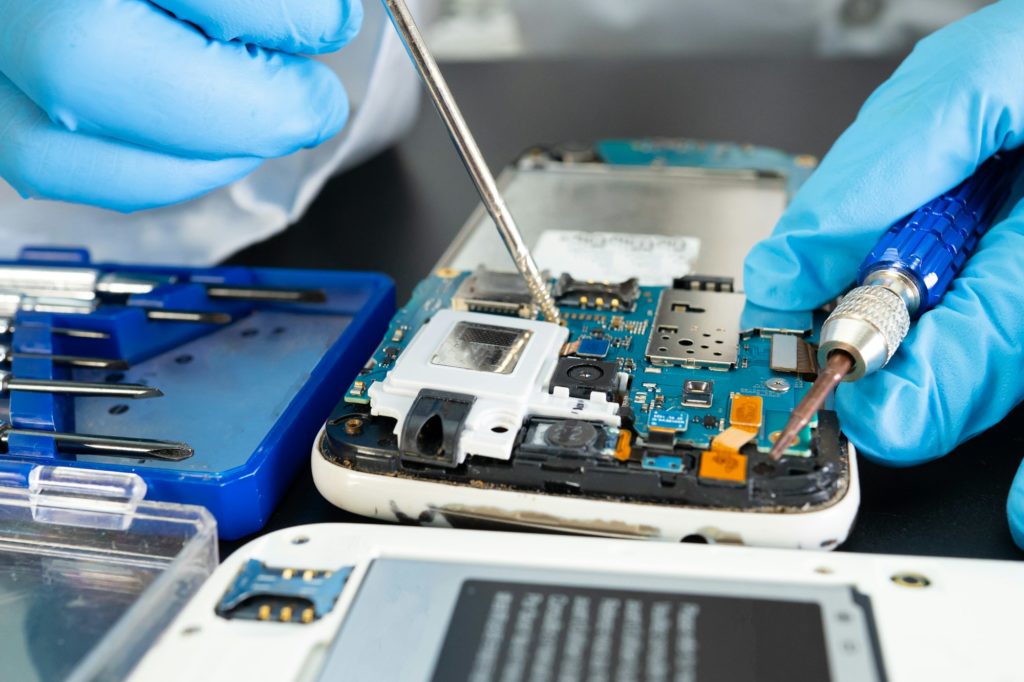 Technician repairing inside of mobile phone by soldering iron